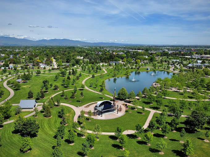 Aerial view of a park with a pond, stage, and multiple sidewalk paths.