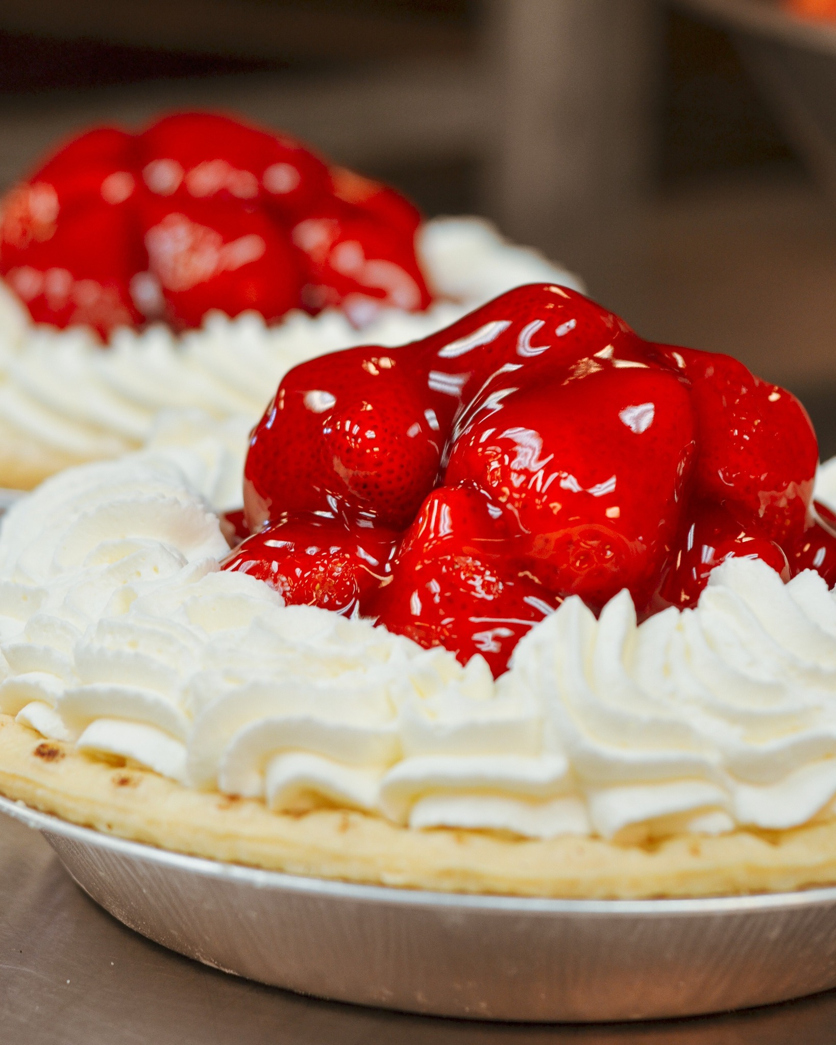 Pie with white frosting, topped with glazed-looking strawberries.