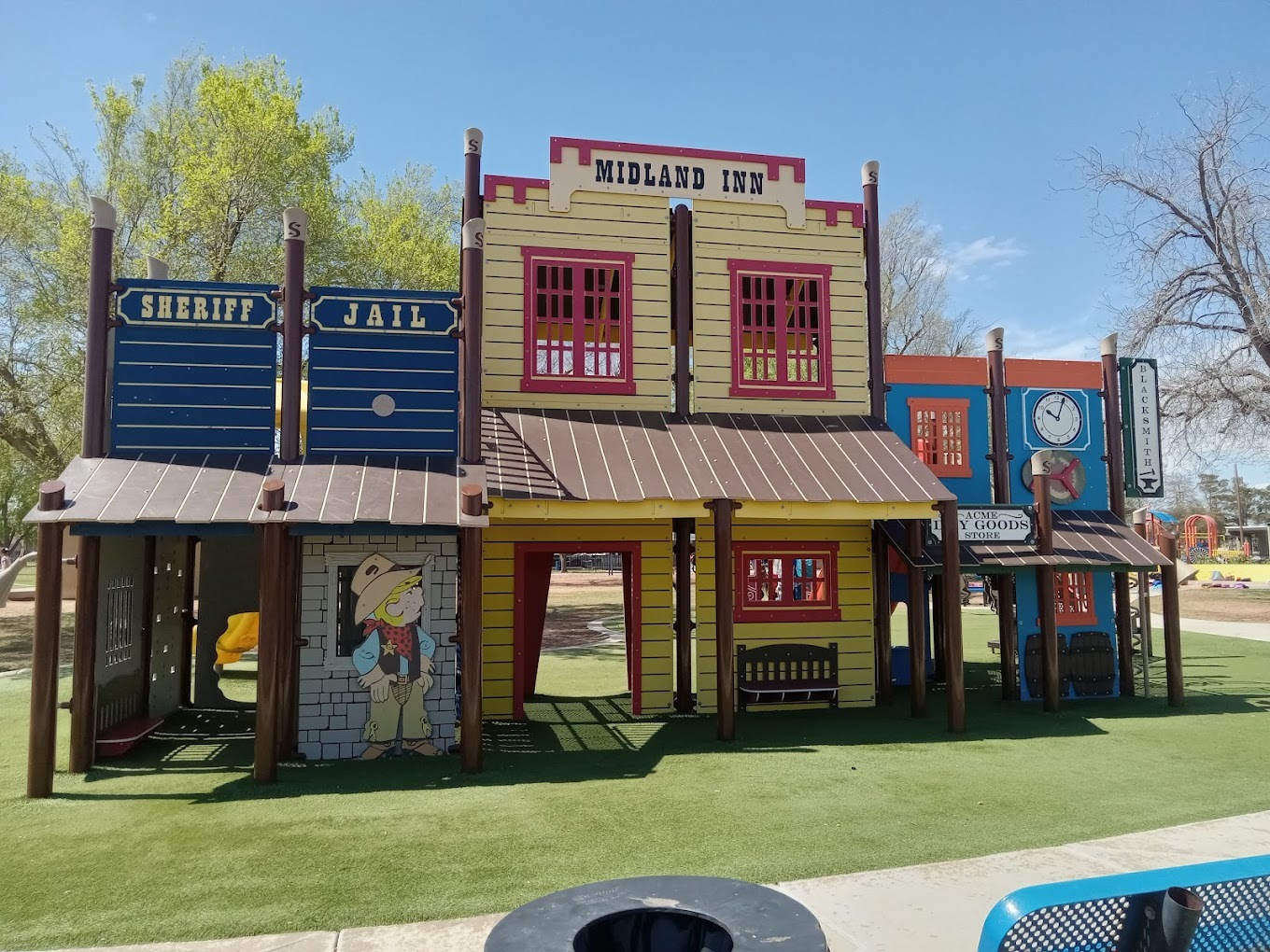 An outside view of a playground that is made to resemble an line of old time businesses.