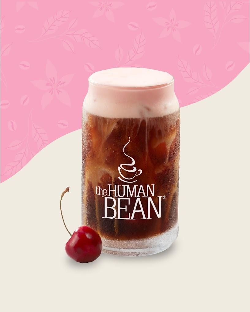 A view of a drink in a glass cup with a lot of foam setting on the top of the beverage.
