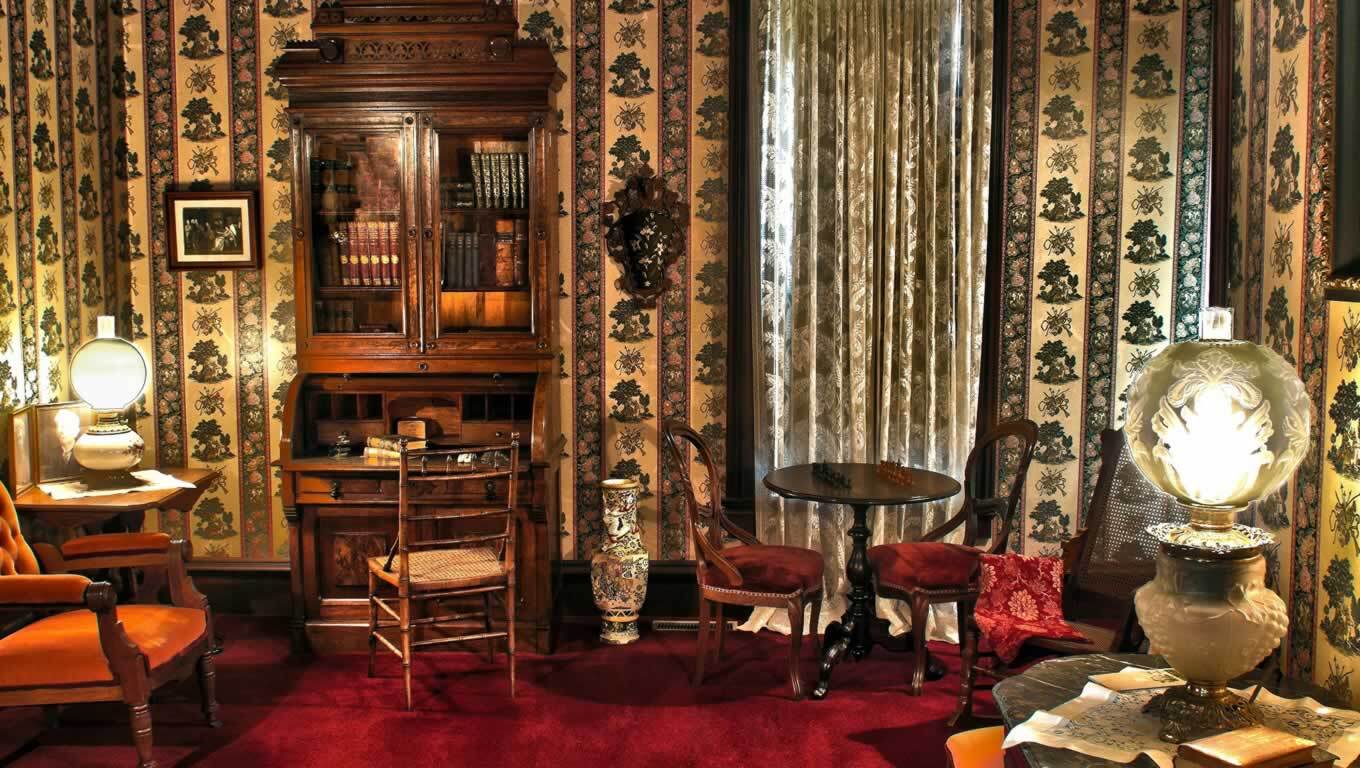 Room full of ornate antique chairs, shades, and lamps.