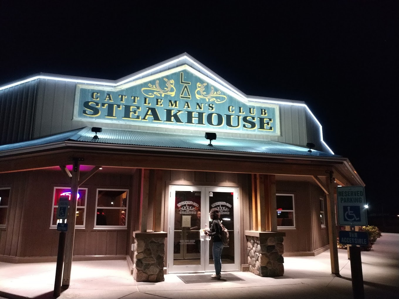 Saloon styled bar and grill entrance with a large lighted green sign.