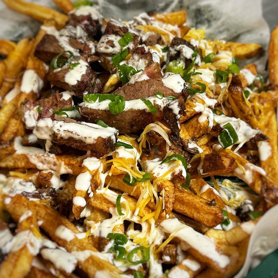 Steak and fries with cheese and sauce.