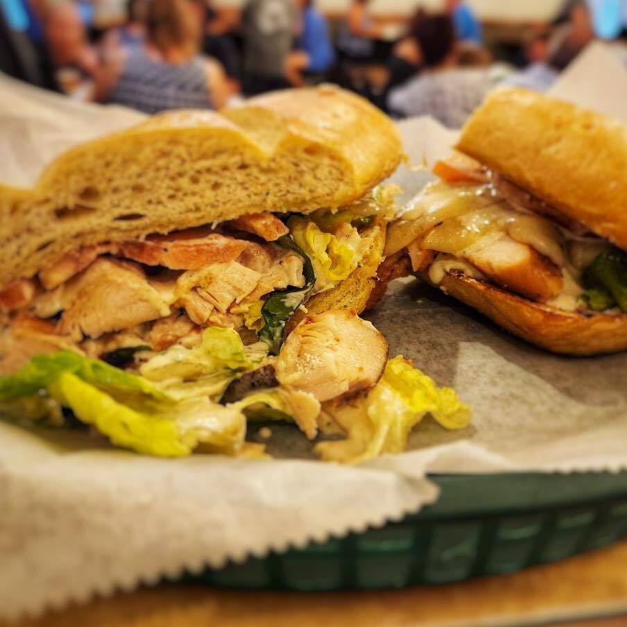Close view of two sliced sandwiches with chicken and lettuce.