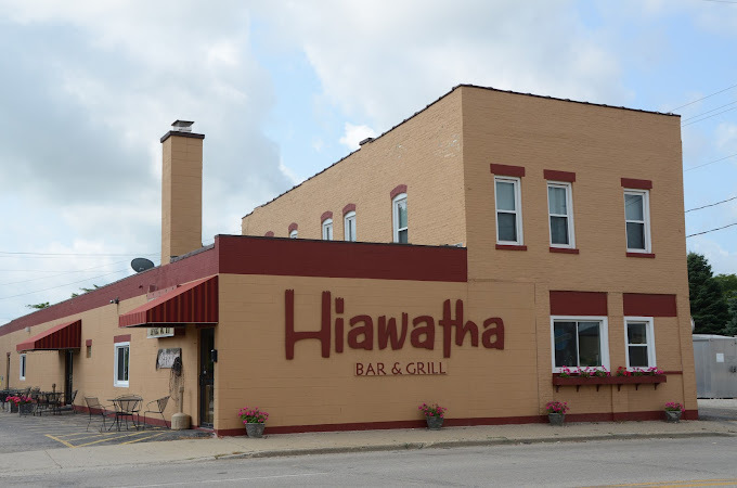 An outdoor view of a bar and grill, a brick building with large red lettering on the side reading "Hiawatha Bar & Grill"