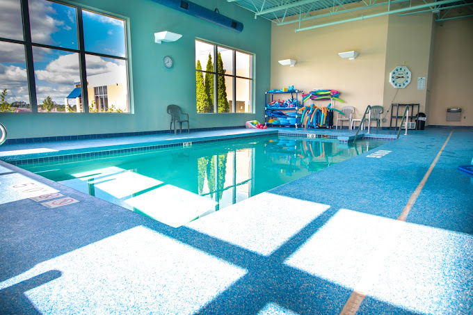 A view of an small indoor pool complete with equipment for the pool in the back of the room.