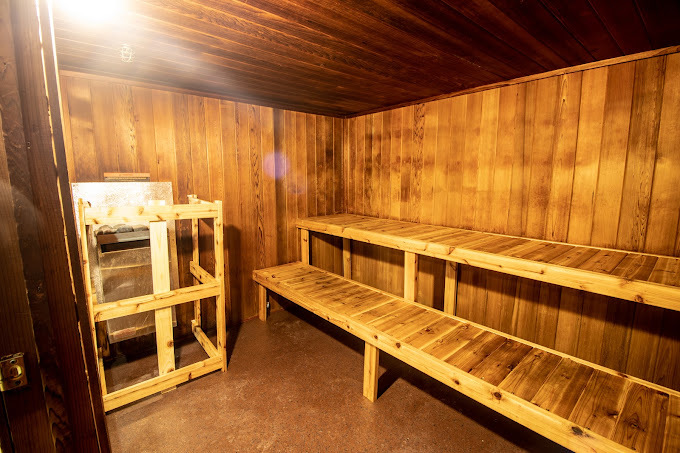 An inside view of a sauna room, a small room with wood paneling and wooden benches.