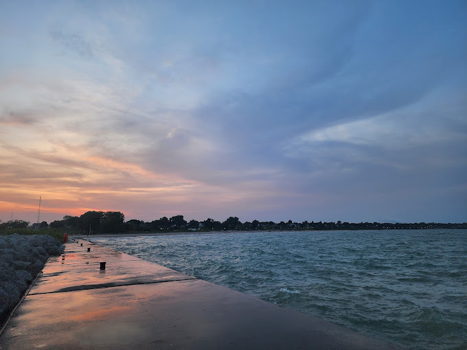 A view of a beach with the sun setting.