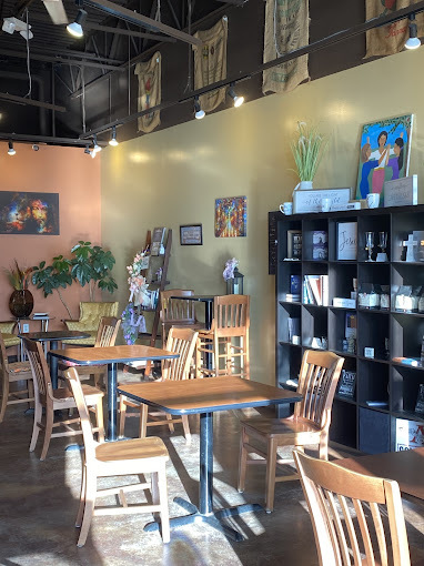 An indoor view of a coffee house sitting area with lots of natural light, and art fills the walls.