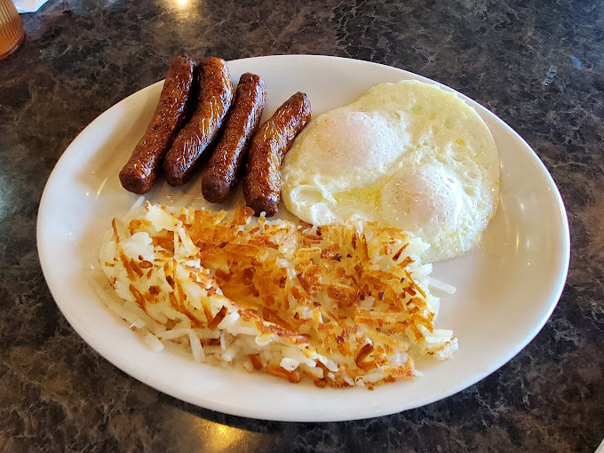 Eggs, sausage, and hashbrowns on a white plate.