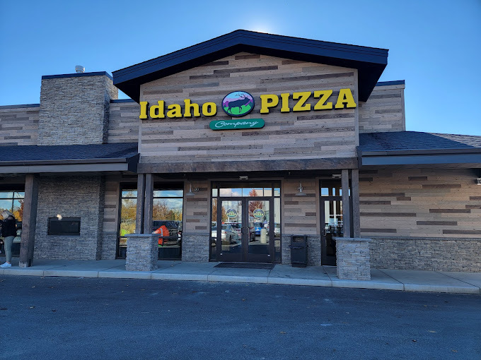 Exterior view of a wood and brick type building with black accents. Entrance sign reads "Idaho Pizza."