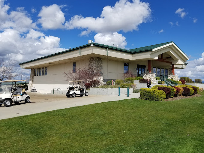 Exterior view of golf course entrance building. Golf carts are close to the entrance and grass is seen in the photo.