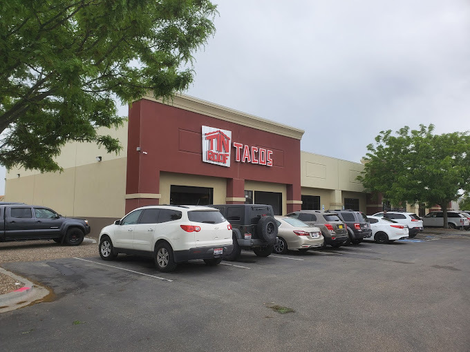 Exterior corner view of a red and beige building. Parking lot and cars can be seen on the bottom half of the image.