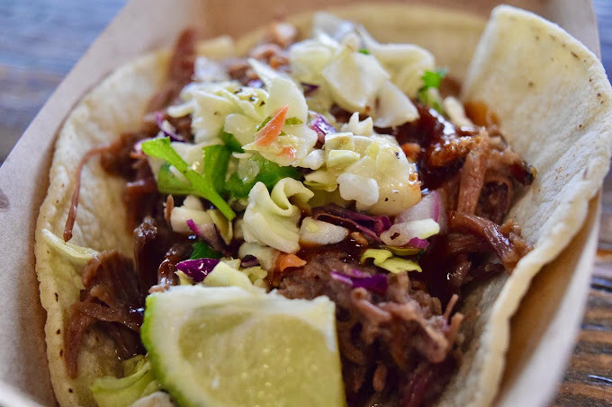 Extreme close up of a taco with lime, meat, and greens.