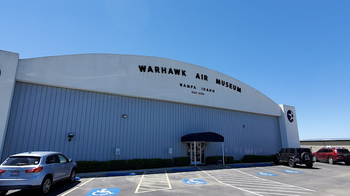 Exterior view of a garage type building that's blue and white. Accessibility parking is seen on the bottom half of the image, near the entrance.
