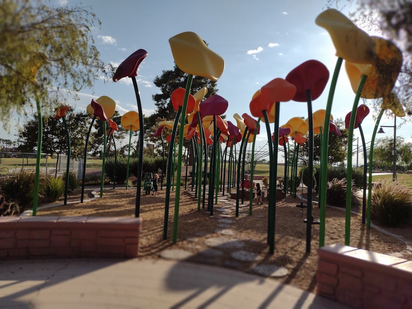 A view of a park art installation, metal flowers made to look ginormous.