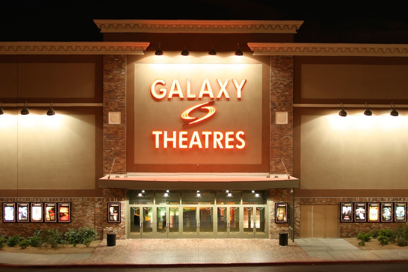A brown and beige building with brick detailing with a very large red sign reading "Galaxy Theatres"