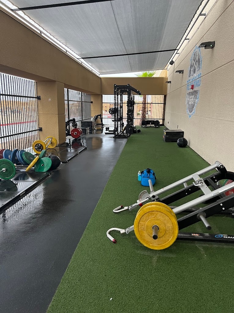 A view of an outdoor gym area with turf, and a selection of equipment.