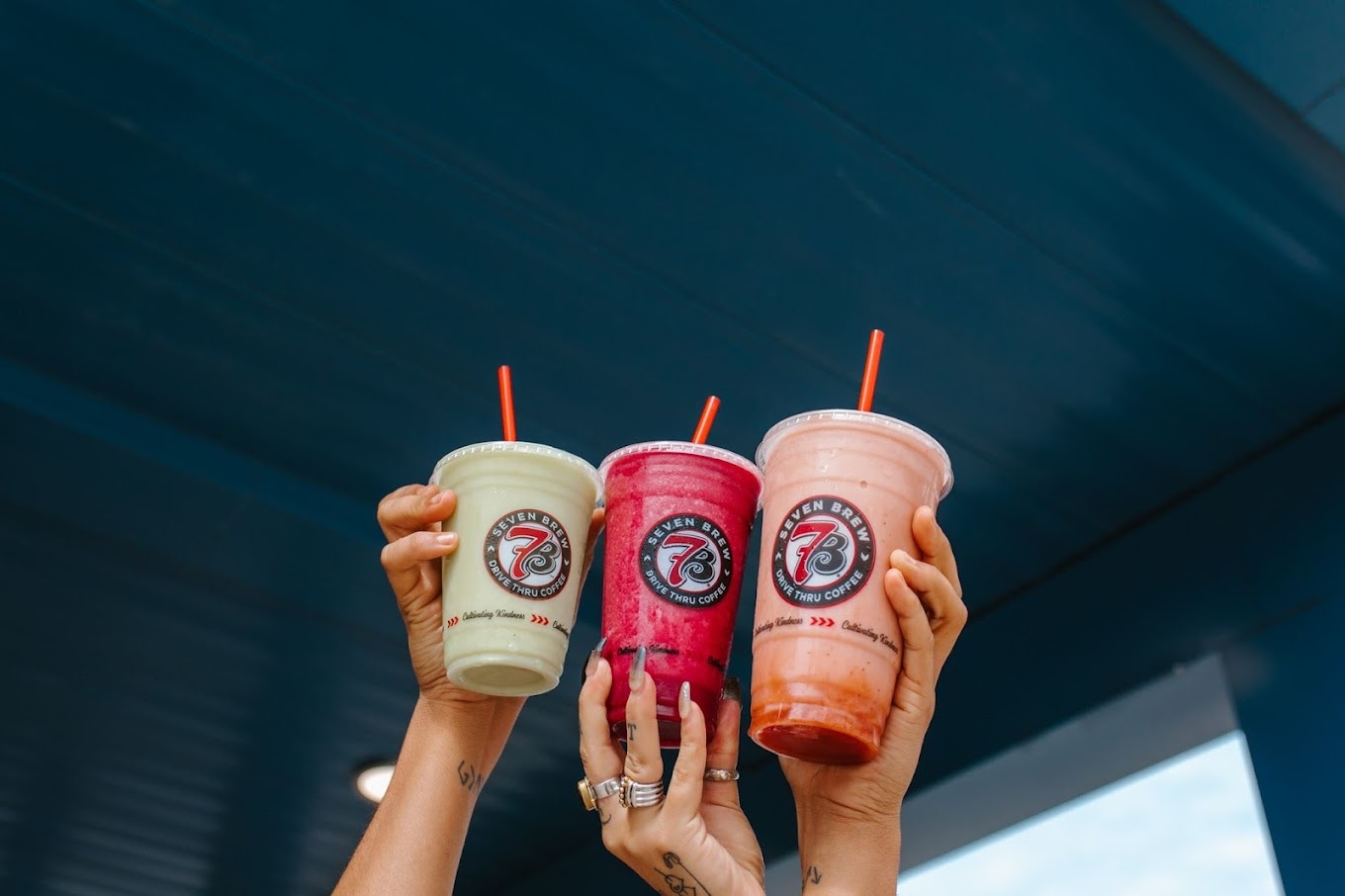 three girls holding their specialty drinks together as a group to cheers.