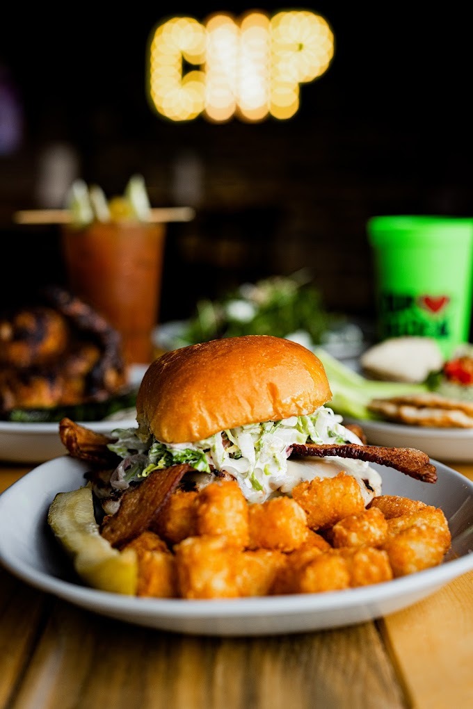 A white plate with a burger and tater tots on the side.