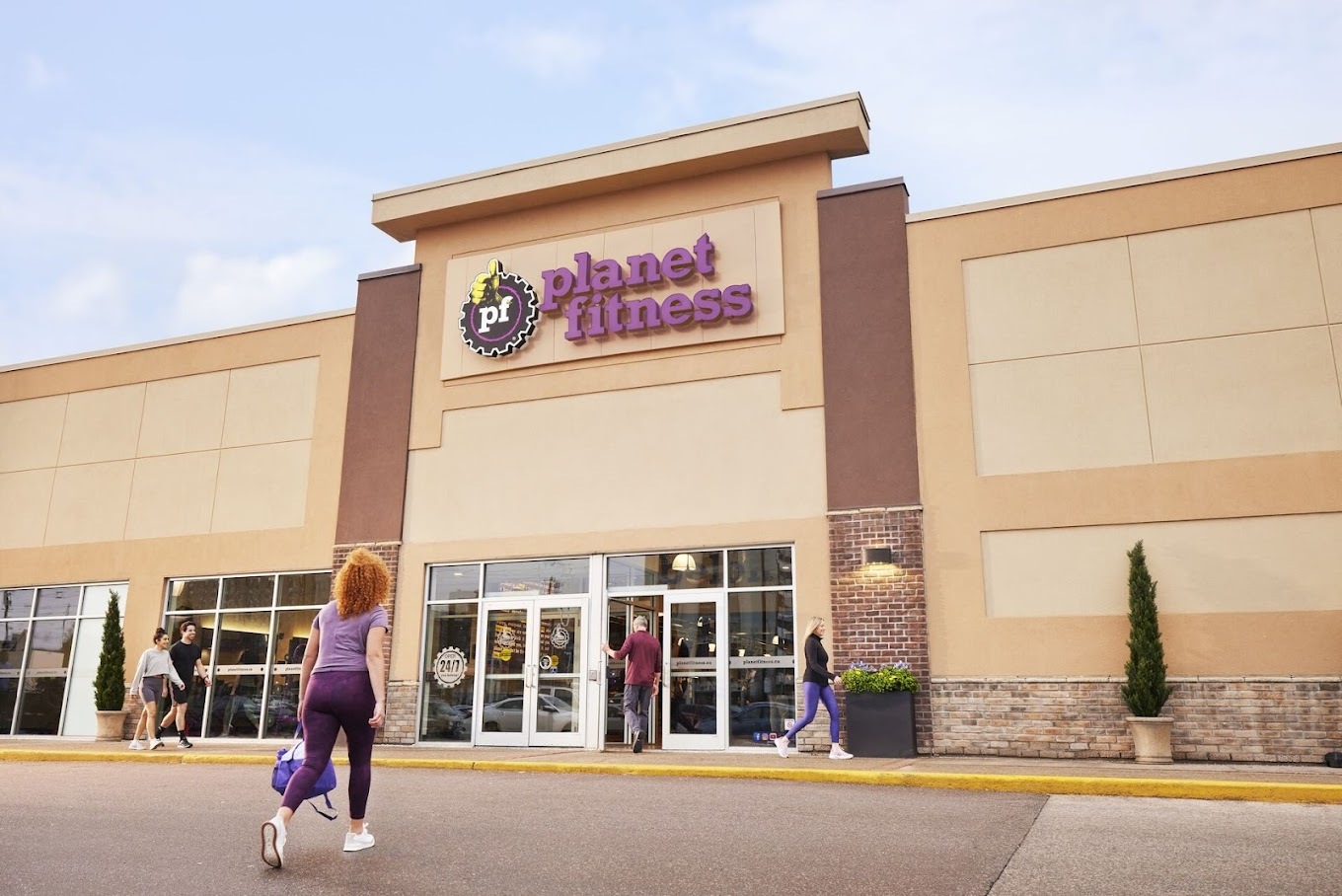 Large beige building with a large sign reading "Planet Fitness" in purple lettering above the entrance doors.