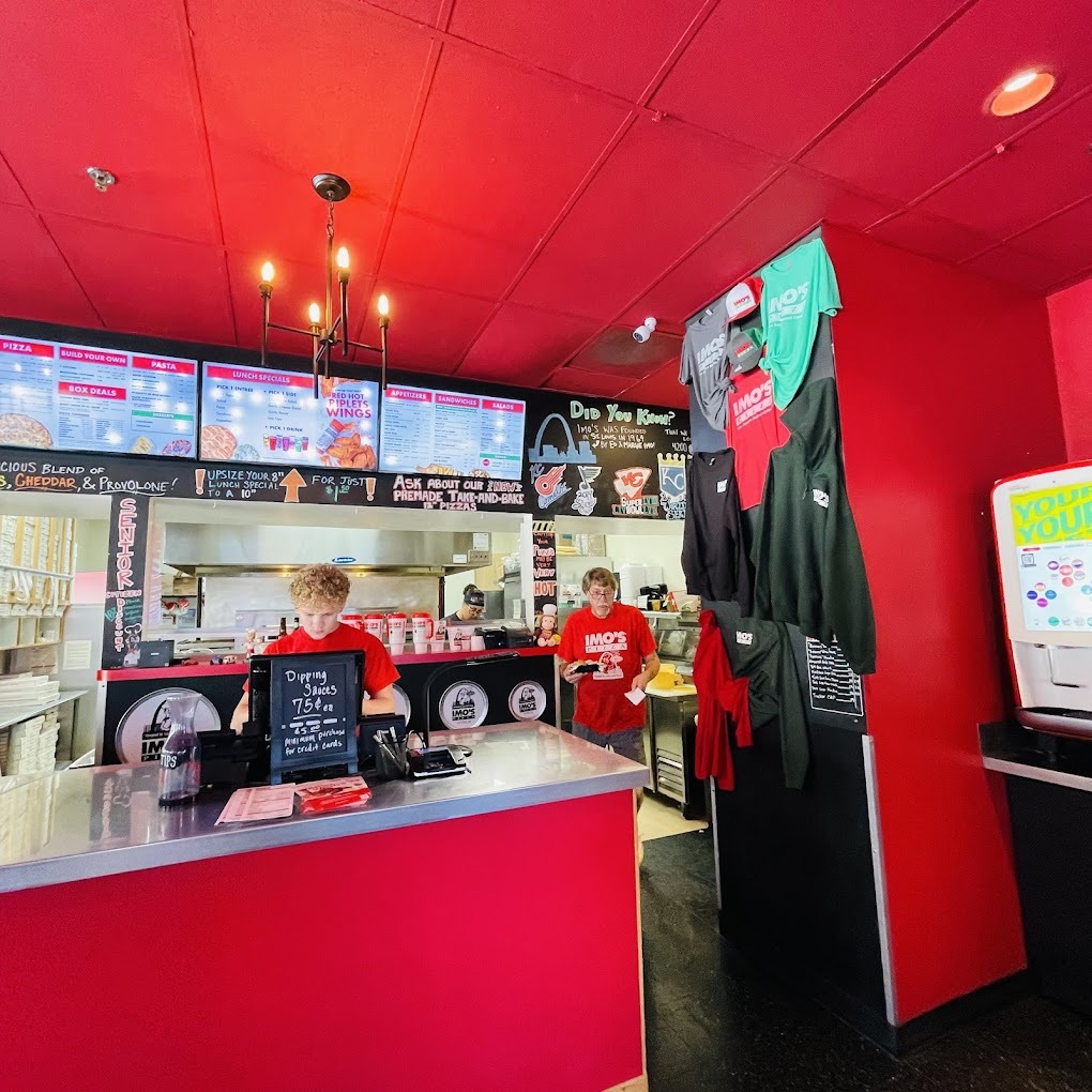 A red room with a red checkout counter and three tv's for menu's behind the POS system.