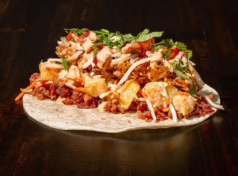 A loaded taco opened laying flat on a black background.