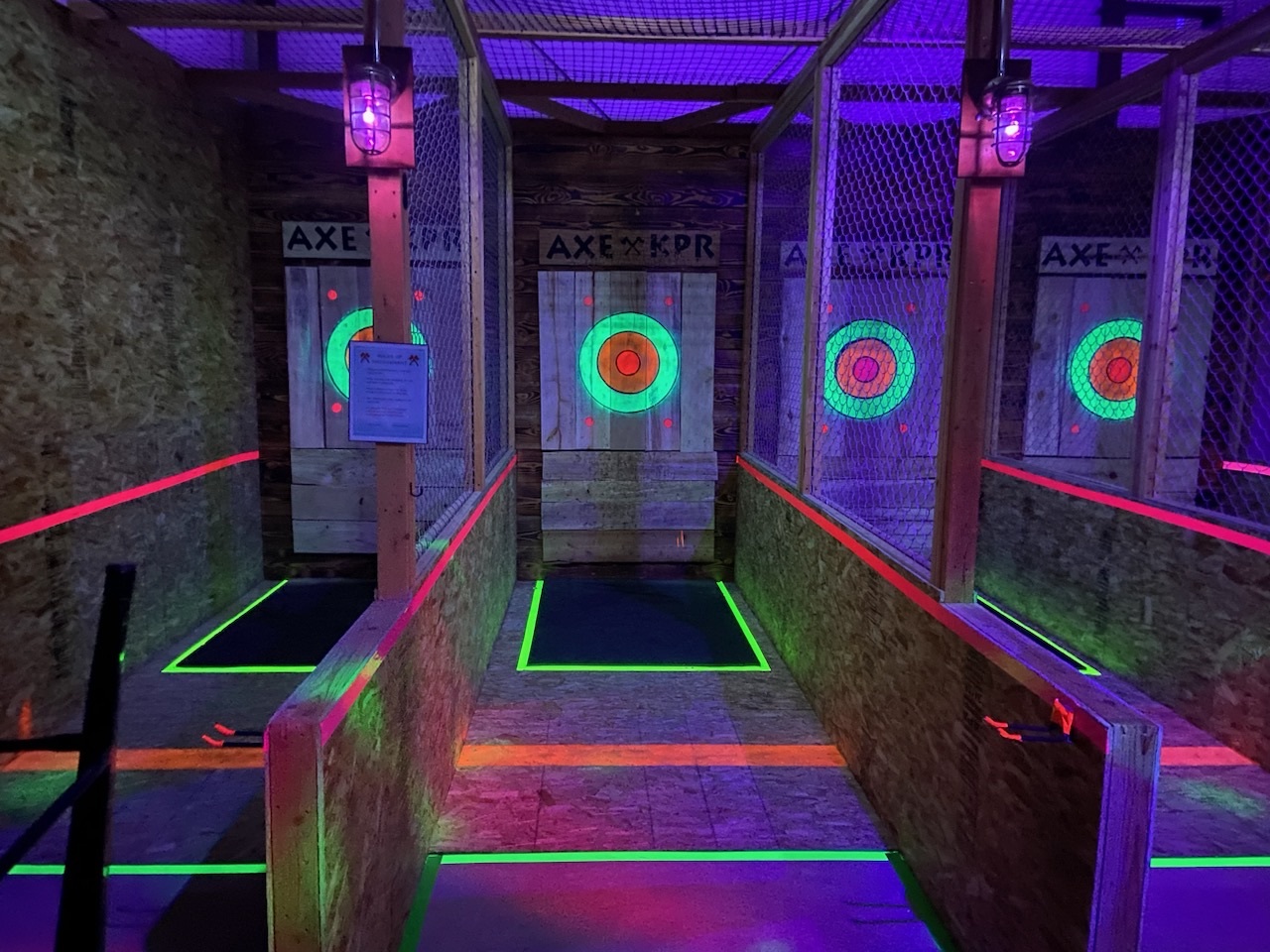 An indoor view of targets that are illuminated by black light and glowing a neon color.