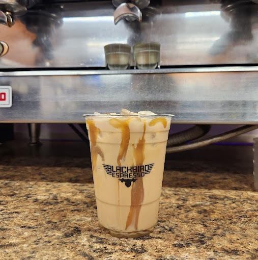 A view of a coffee with caramel, the coffee machine in the background silver.