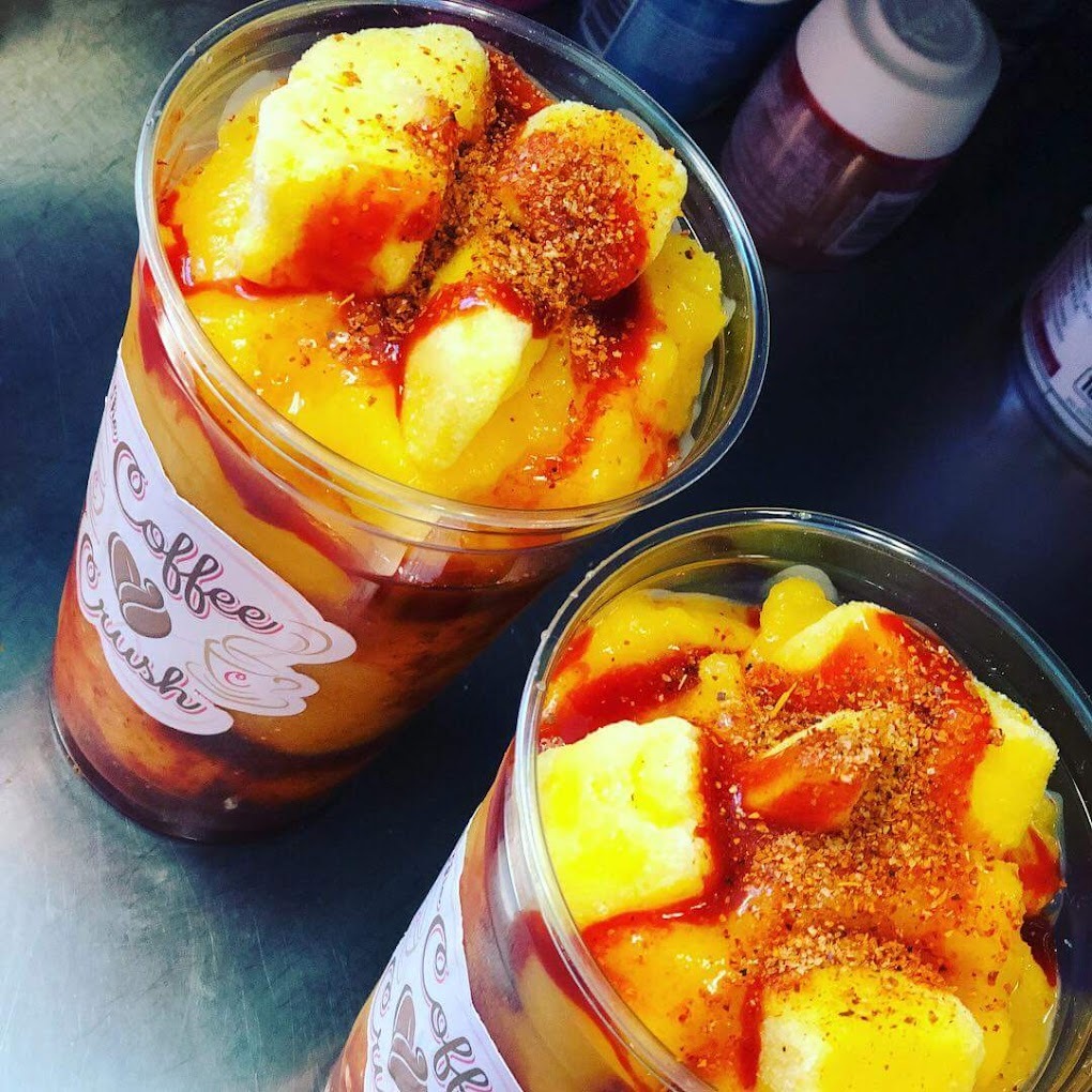 A view of two smoothies topped with mango, chamoy, and spices.