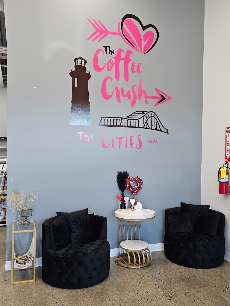 An view of a sitting area in a cafe with grey walls and pink lettering on the wall reading "Coffee Crush"