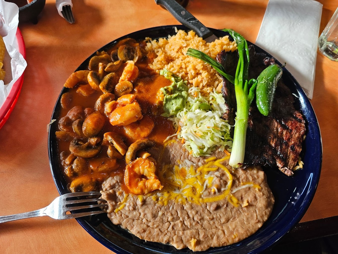 A black plate filled with refined beans, rice, and pozole.