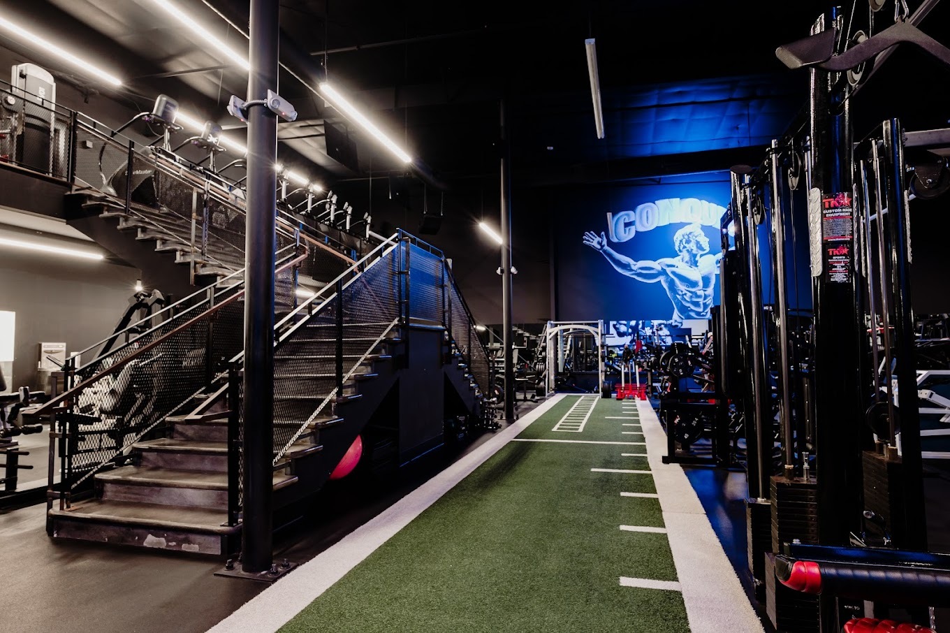 An indoor view of a split level room, filled with all kinds of workout equipment lining the walls of the gym.