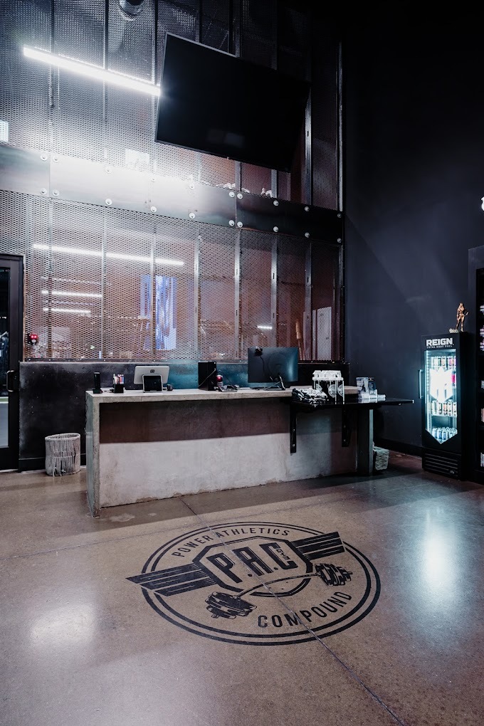 A view of a gym's front desk waiting area, a modern sleek, and mostly concrete room.