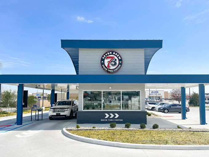 Exterior view of a drive around blue and white brick building with sun shades.