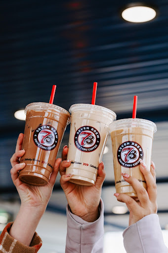 Three hands holding three different iced drinks with red straws.