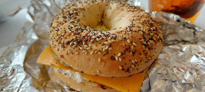 Extreme close view of a seasoned bagel with cheese wrapped in foil.