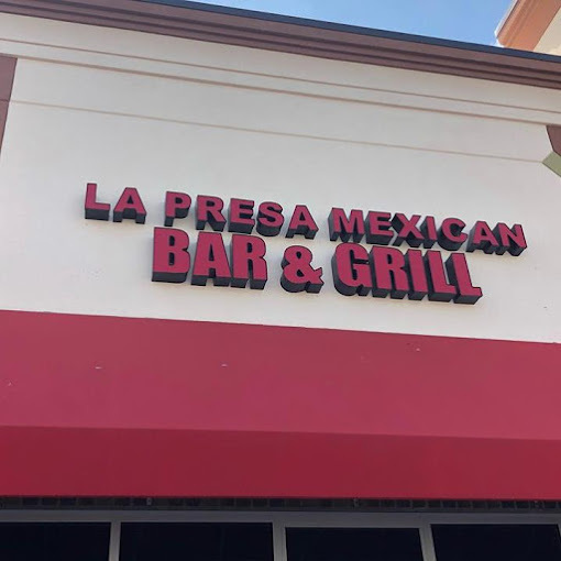 Exterior close view of a red sign above the building entrance. It reads "La Presa Mexican Bar and Grill."