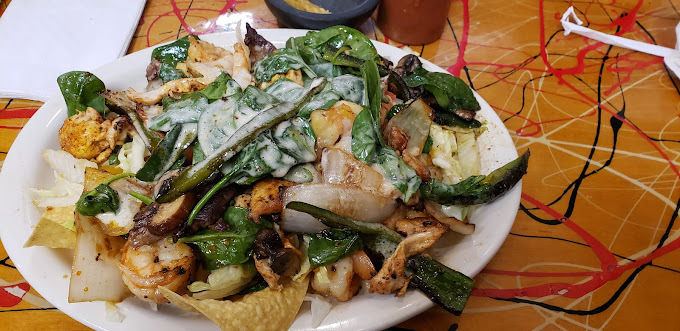 Close view of dish made with shrimp, greens, and more on a white plate.