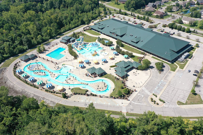 Aerial view of a green roofed building, lazy river, pool, and waterslides.
