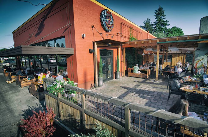 Exterior corner view of an orange building with brown sun shades and a large outdoor patio.