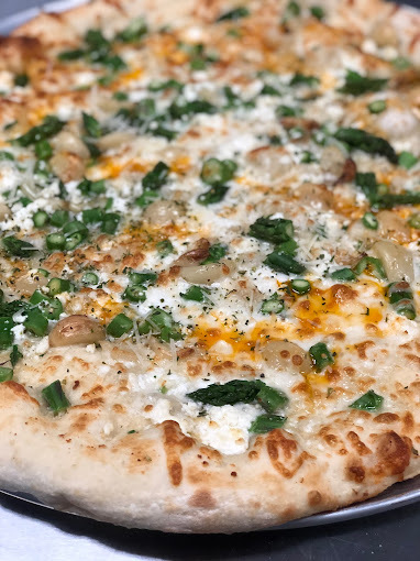 Extreme close view of a pizza with greens and cheese.