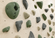 Close-up of an indoor rock climbing wall featuring textured climbing holds in muted green, gray, and beige tones mounted on a light wood panel.