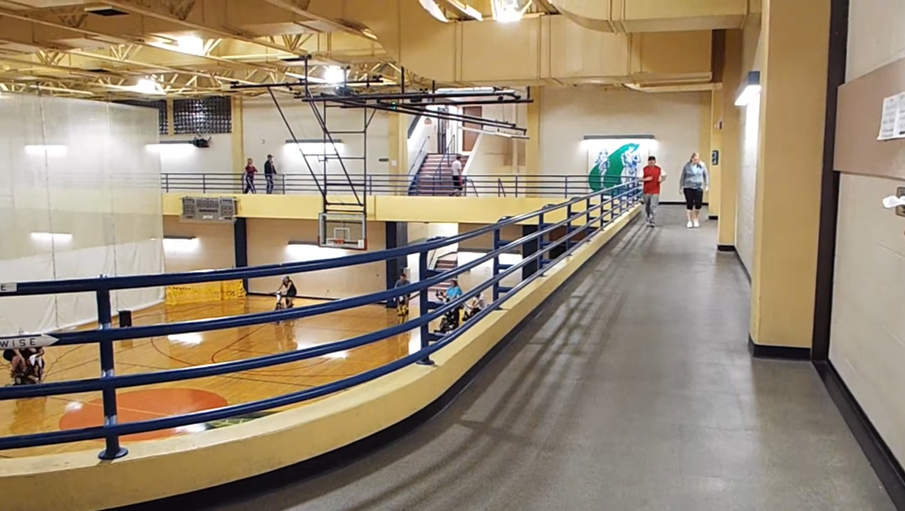 A view of a basketball court from the elevated walking track around the large gym court.