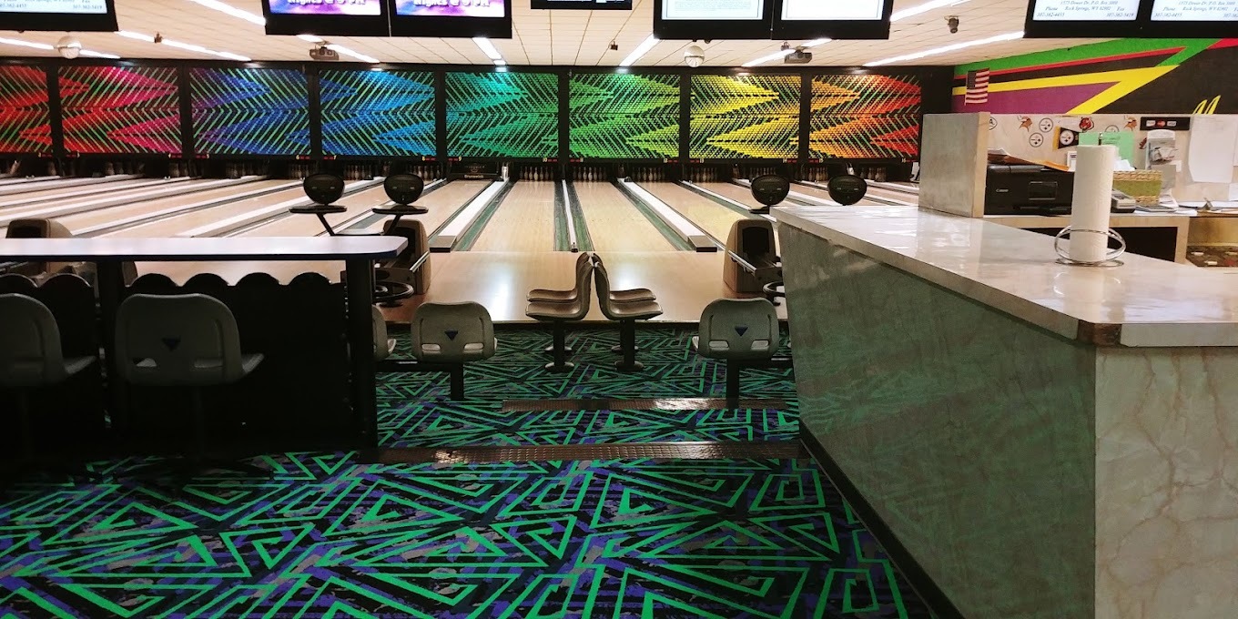 A view of a a bowling lane counter with rainbow designs on the back of the bowling lanes.