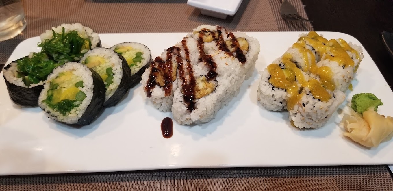 A white plate consisting of three different flavors of sushi rolls.