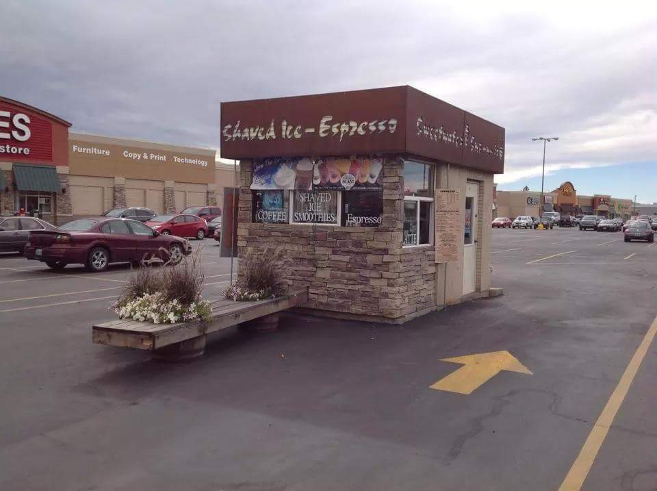 An outside view of a small drive thru coffee house with a brown roof and white lettering on the roof.