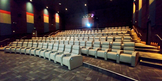 A view of an very large theatre with grey luxury recliner seating.