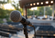 Close-up of a stage microphone on a stand with an outdoor amphitheater and performance stage softly blurred in the background.