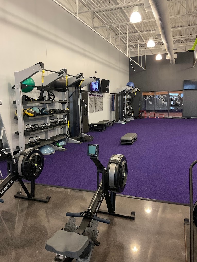 A room with a purple rug featuring bikes and a rack of weights inside of the gym room.